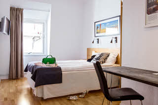 Queen bed and desk in standard room at Scandic Stortorget